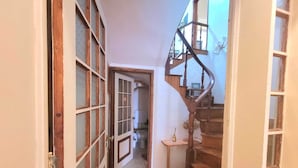 Ein schmaler Flur mit einer Holztreppe, die zu einer oberen Etage führt.