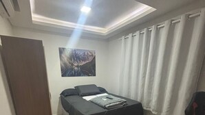 Une chambre à coucher avec un lit, un bureau, une armoire et un tableau accroché au mur.