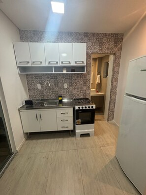 A compact kitchen with white cabinets, a gas stove, and a built-in oven. - Loft Trevos, Casa Aconchegante. (Itajaí)