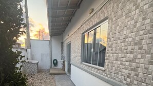 Un étroit sentier mène à un bâtiment doté d’une façade en pierre et d’une grande fenêtre.
