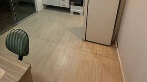 Une cuisine de taille réduite avec des meubles blancs, un four encastré et un réfrigérateur.
