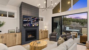 Una sala de estar moderna con chimenea, asientos cómodos y una gran pantalla de televisión.