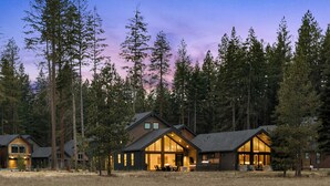 Una cabaña de troncos moderna con ventanas grandes y un interior espacioso, rodeada de altos pinos.