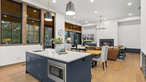 Een moderne keuken met een centraal eiland, grote ramen en een open haard.