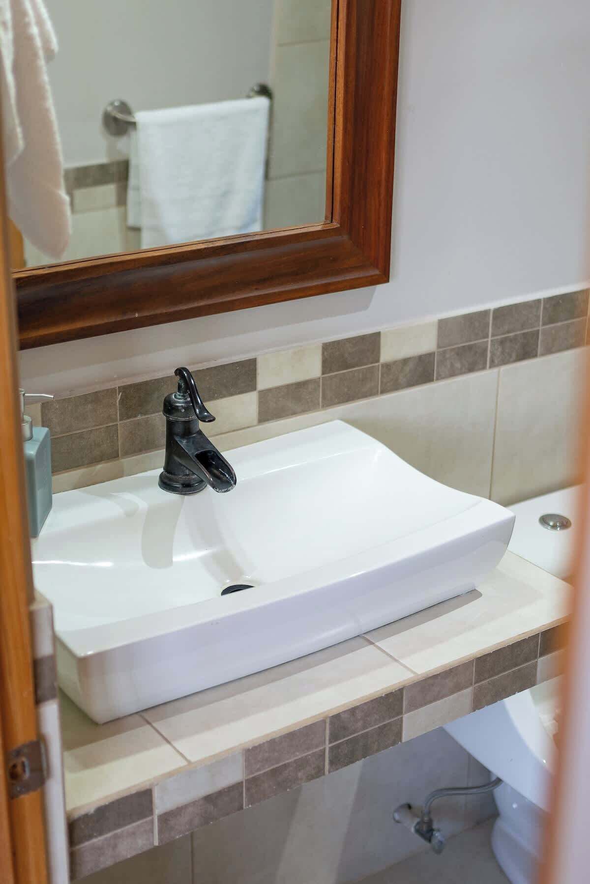 A bathroom with a white sink, a mirror, and a towel rack.