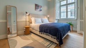 A bedroom with a bed, bedside table, lamp, mirror, window, and a plant. - FLH Heart of Rossio Flat III (Lisboa ciudad)