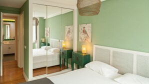 A bedroom with a bed, bedside tables, a mirror, and artwork on the wall. - FLH Downtown City Elegance Apartment (Lisboa ciudad)