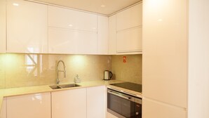 A modern kitchen with white cabinets, stainless steel appliances, and a wooden floor. - FLH Downtown City Elegance Apartment (Lisboa ciudad)