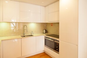 A modern kitchen with white cabinets, stainless steel appliances, and a wooden floor. - FLH Downtown City Elegance Apartment (Lisboa ciudad)