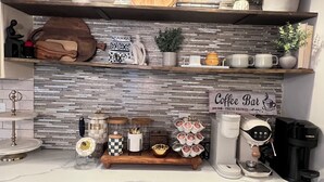 A kitchen with marble countertops, a coffee bar sign, and various kitchen appliances and decor.