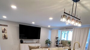 A modern kitchen with a large island, built-in appliances, and a flat-screen TV.