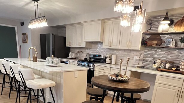 A modern kitchen with a central island, bar stools, and pendant lighting.