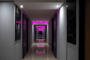 A modern hallway with reflective flooring, a central light source, and a series of doors on either side.