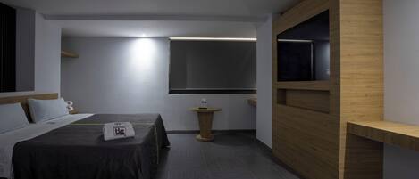 A hotel room with a bed, bedside table, and a built-in TV shelf.