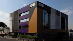 A modern hotel building with 'HOTEL' signage on the facade, multiple windows, and a street in front.