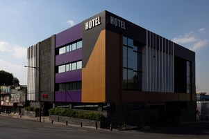 A modern hotel building with 'HOTEL' signage on the facade, multiple windows, and a street in front.