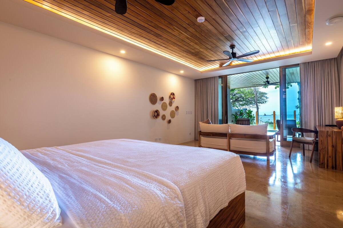 Un dormitorio moderno con una cama grande, techo de madera y vistas al exterior.