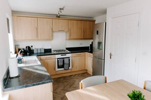 A compact kitchen with wooden cabinets, a stainless steel refrigerator, a gas stove, and a dishwasher.