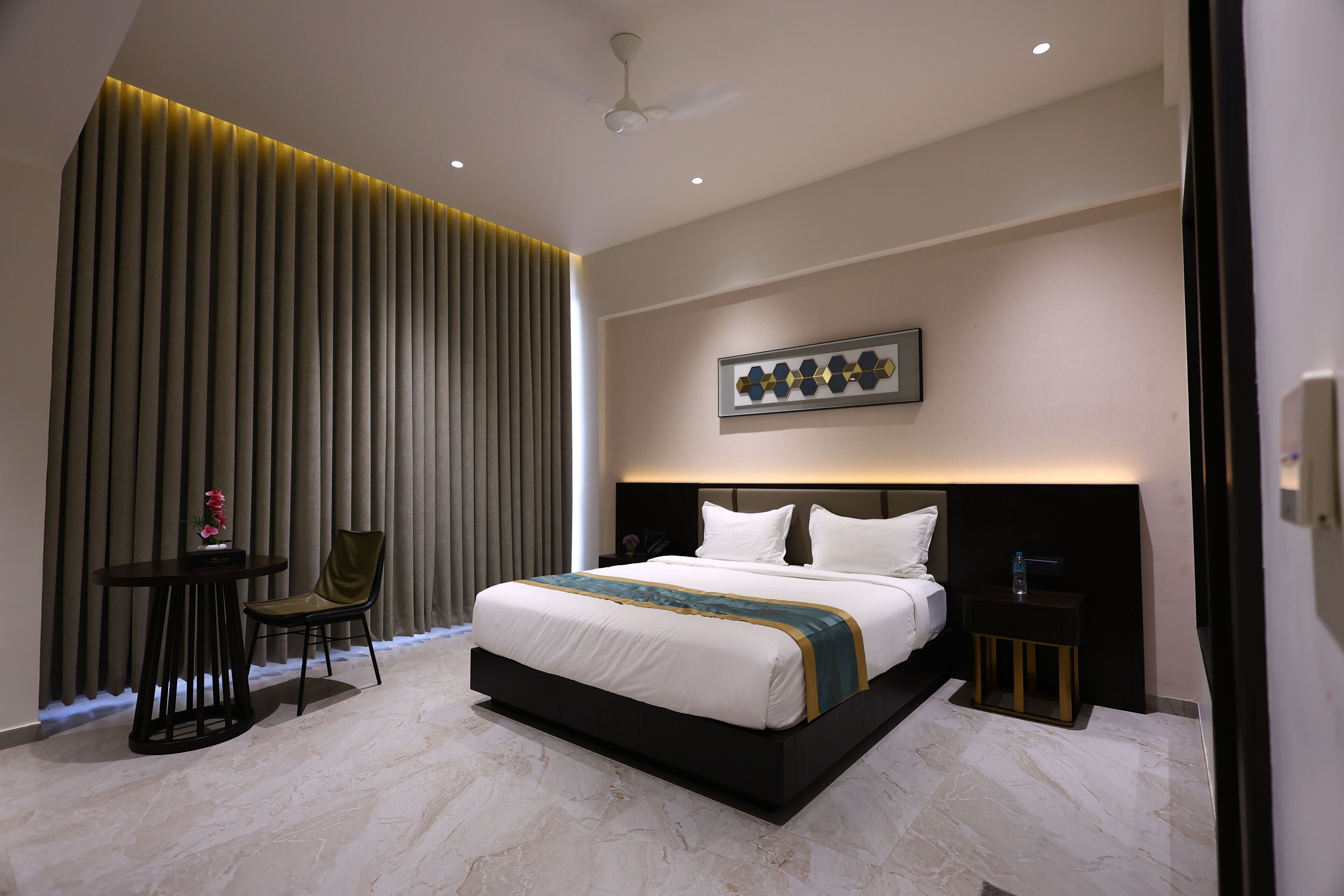 Una habitación de hotel moderna con una cama grande, una mesita de noche, una silla y un adorno en la pared.