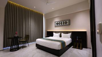 Una habitación de hotel moderna con una cama grande, una mesita de noche, una silla y un adorno en la pared.