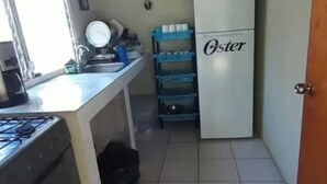 Una cocina compacta con estufa a gas, un lavabo, un refrigerador y un mueble de almacenamiento azul.