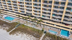 Un hôtel de grande hauteur doté de nombreux balcons, d’un espace piscine et offrant une vue sur la plage.