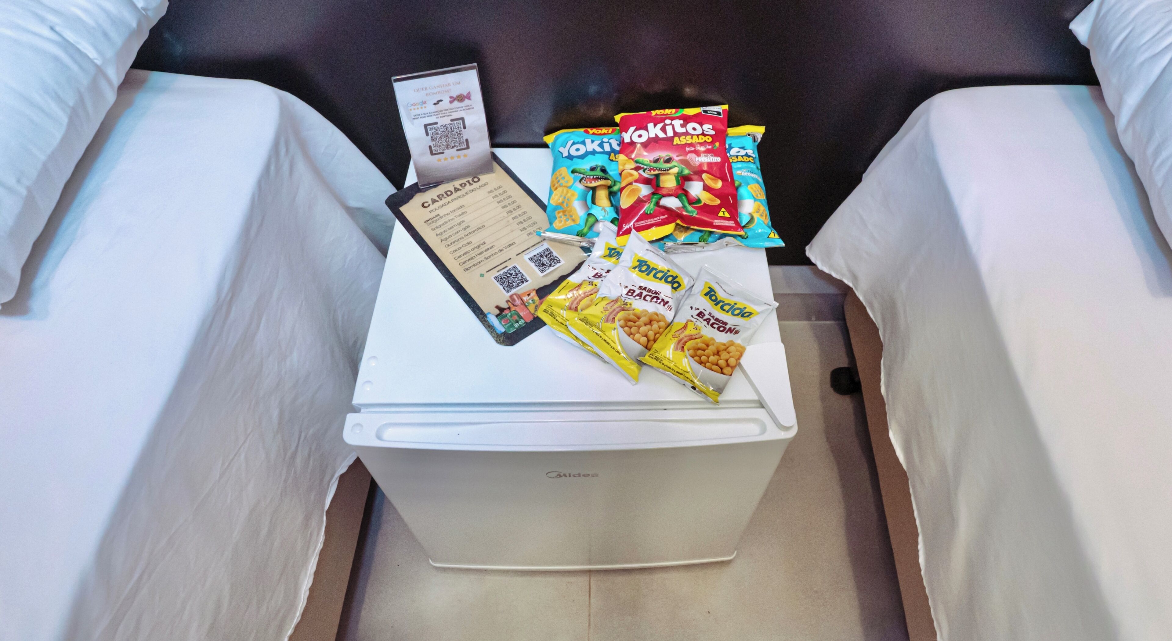 A white minibar with snacks, a QR code, and a card.