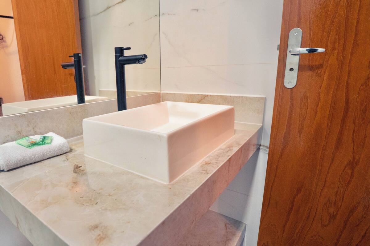 A bathroom with a white sink, a towel, and a mirror.