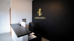 Una reception con una parete nera, un cartello con scritto 'HOTEL LUX' e un'indicazione 'CHAVES' sopra.