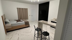 Una camera compatta con un letto, un tavolino, due sedie e un angolo bagno.