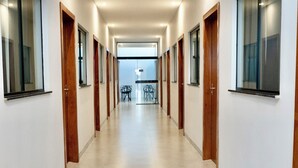 Un corridoio con porte in legno, un divisorio in vetro e una zona salotto con sedie.
