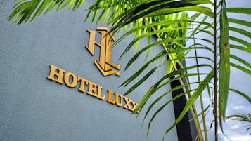En vägg med texten ”HOTEL LUXY” och en stiliserad logotyp i form av bokstaven ”L”.