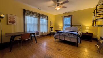 A bedroom with a bed, a desk, and a chair.