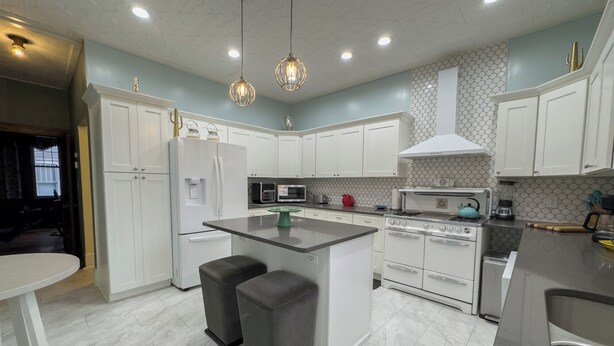 A modern kitchen with white cabinets, a central island, and a stove. - The Lodge (Sutton)
