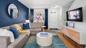 A modern living room with a sofa, coffee table, and TV. - Old Town Living- Xcape to Vibrant Old Town (Alexandria)
