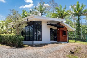 A modern house with large glass windows, a wooden exterior, and a gravel driveway. - Villa 2 (2BR) w/Pool • Near Downtown Turrialba (Turrialba)