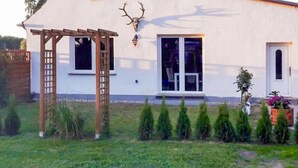 Un bâtiment blanc orné d’une pergola en bois, d’un crâne de cerf en guise de décoration, et d’une fenêtre offrant une vue sur le paysage.