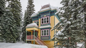 Une maison en bois aux couleurs vives, entourée d’arbres couverts de neige.