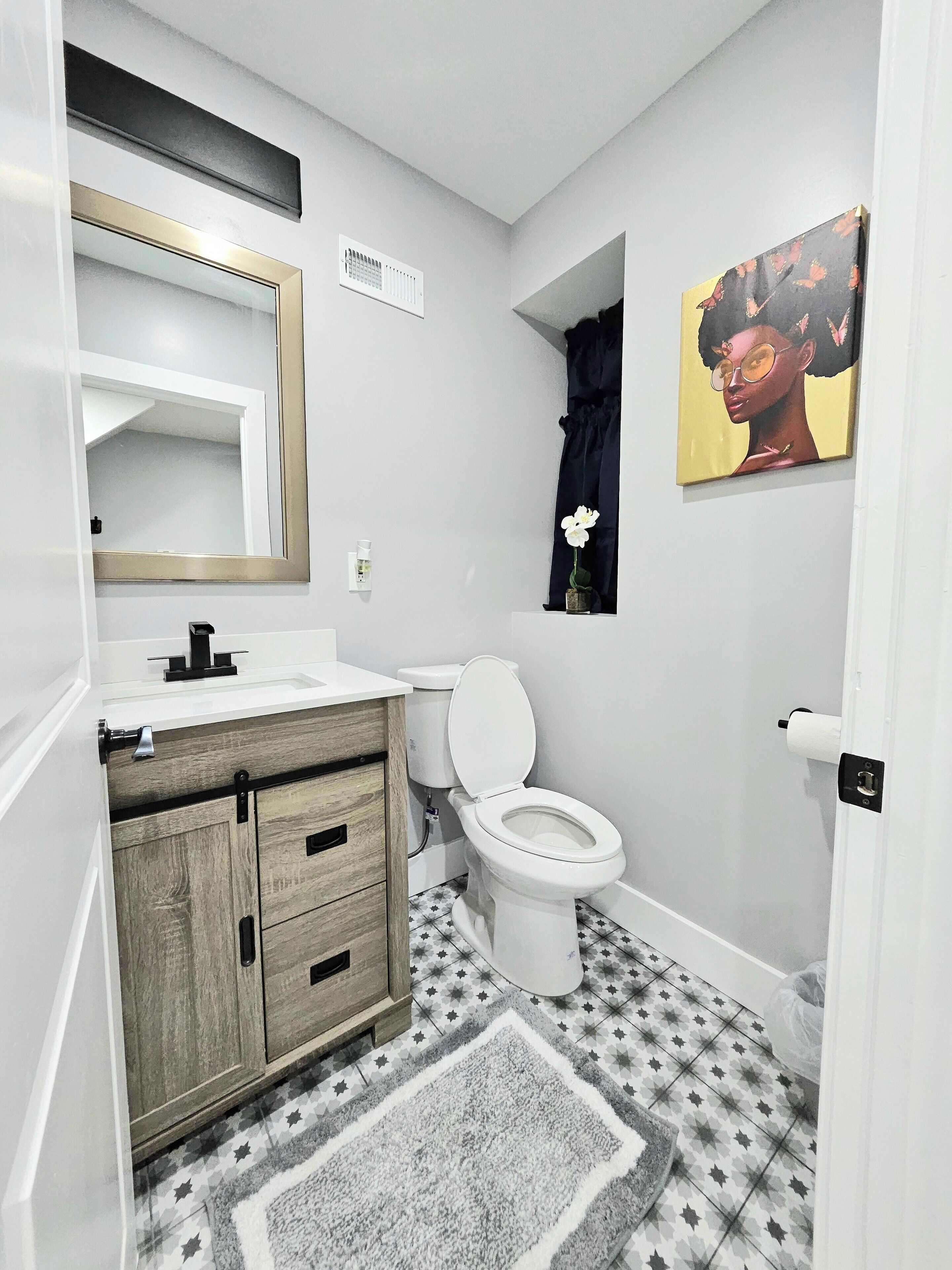 A bathroom with a toilet, sink, mirror, and a star-patterned floor.