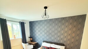 Une chambre d’hôtel avec un lit, un bureau, une chaise et un radiateur.