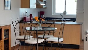 A modern kitchen with a dining area, featuring a glass table, metal chairs, and a vase with flowers. - Villa Las Coloradas - An Ideal Retreat in Playa Blanca (Playa Blanca)