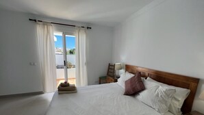 A hotel room with a large bed, a wooden headboard, a nightstand, a lamp, and a view of the outdoors through a sliding door. - Villa Las Coloradas - An Ideal Retreat in Playa Blanca (Playa Blanca)