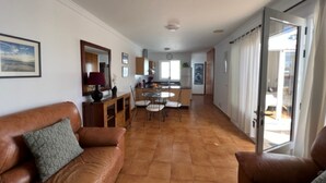 A spacious living area with a brown leather sofa, a dining table with chairs, and a kitchen in the background. - Villa Las Coloradas - An Ideal Retreat in Playa Blanca (Playa Blanca)