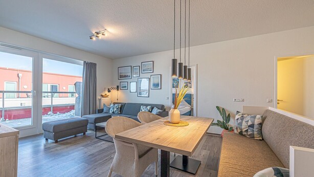 Una sala moderna con una mesa de comedor, sofá y vistas al exterior.
