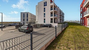 Un moderno edificio de apartamentos con estacionamiento y un campo cubierto de césped.