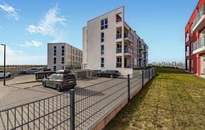 A modern apartment building with a parking area and a grassy field. - Nice apartment in OstseeResort Olpenitz with sauna (OstseeResort Olpenitz)