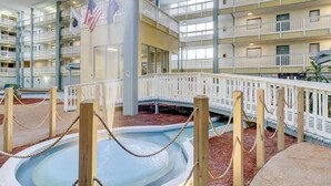 A multi-level indoor atrium with a central pool, balconies, and American flags. - Coastal 2 bed 2 ba Villa - Pools - beach access (Hilton Head Island)