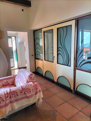 Ein Schlafzimmer mit einem Bett, einem Schrank mit Milchglasfronten und Blick durch ein Fenster.
