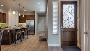 A modern kitchen with a central island, bar stools, pendant lighting, and a stainless steel refrigerator. - 82-85 - Southern Cove Duplex in St George with Hot Tub (Santa Clara)