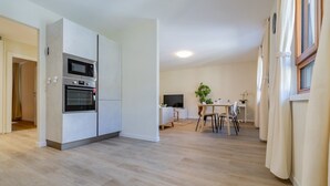 A modern kitchen with built-in appliances, a dining area with a table and chairs, and a small TV. - Leaf Apartment in Zurich Oerlikon (Zürich)